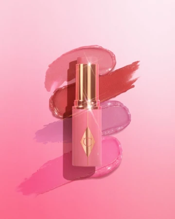 Product shot of a pink lipstick tube with gold accents surrounded by swipes of pink, red, and purple lipstick on a pink background.