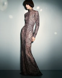 Model with a dark bob haircut posing in a full-length leopard print high-neck gown against a grey studio backdrop.