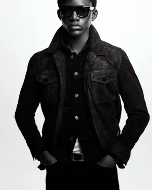 Man wearing dark sunglasses and a dark button-up jacket against a plain white background