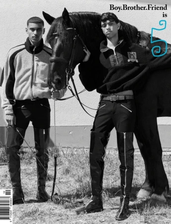 Monochrome fashion shot of two male models posing with a black horse outdoors, wearing black and white jackets, black riding pants and boots.