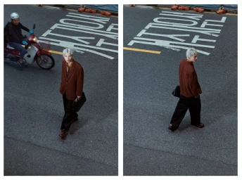 High-angle view of model Hyun Jin Kang walking on an asphalt street with road markings, wearing a brown blazer.