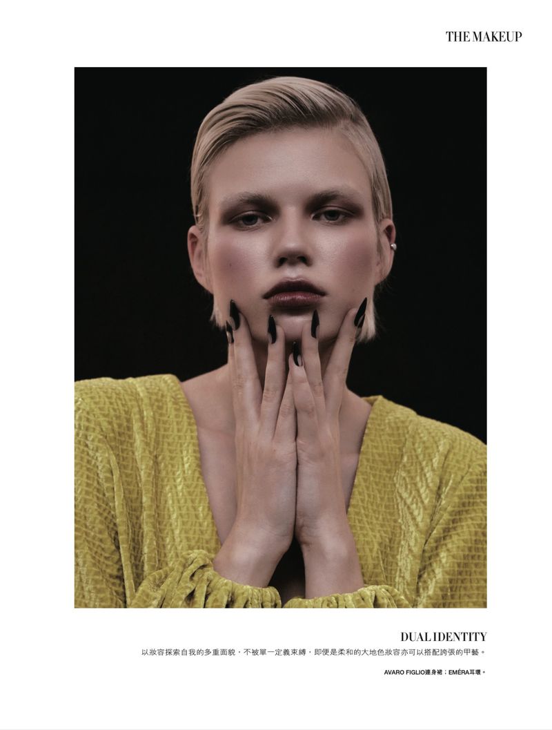 Editorial beauty shot of a woman with dark eye makeup and short blonde hair. She is wearing a yellow textured jacket.