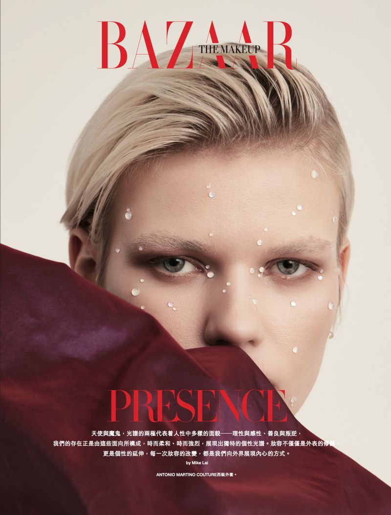 Close-up editorial fashion shot of a woman with white facial paint, short blonde hair, and burgundy fabric. Bazaar The Makeup logo shown.