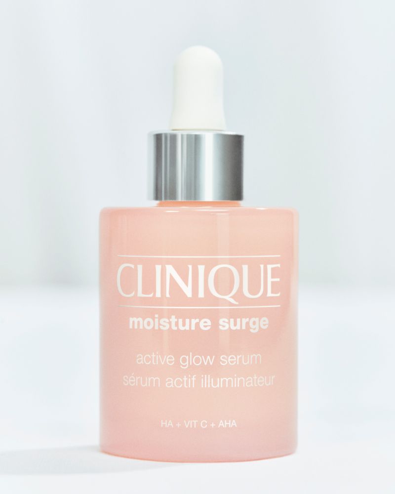 Clinique Moisture Surge Active Glow Serum bottle with a silver and white dropper set against a soft, out-of-focus white backdrop.