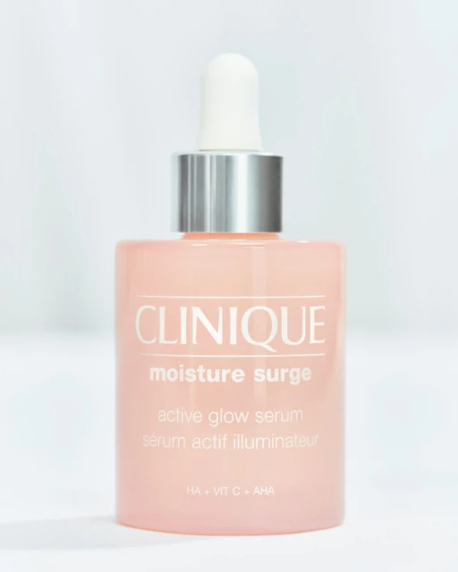 Clinique Moisture Surge Active Glow Serum bottle with a silver and white dropper set against a soft, out-of-focus white backdrop.