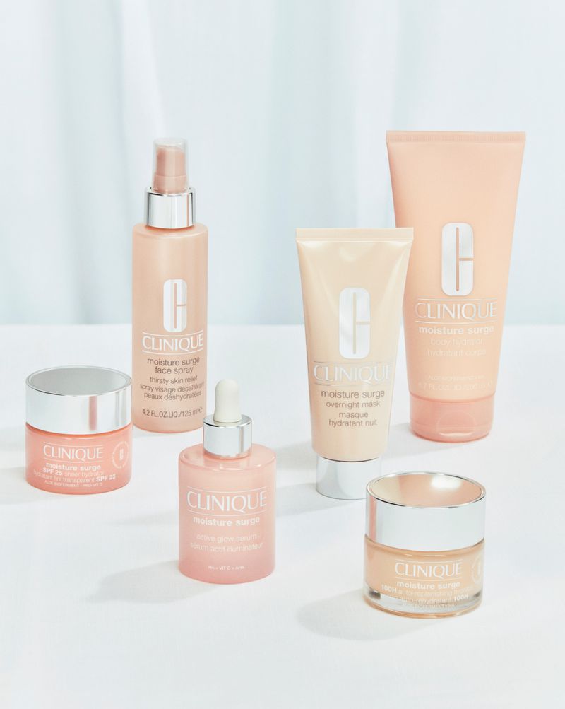 Five Clinique Moisture Surge skincare products are displayed on a white surface, including lotions, sprays, and moisturizers, for beauty and hydration.