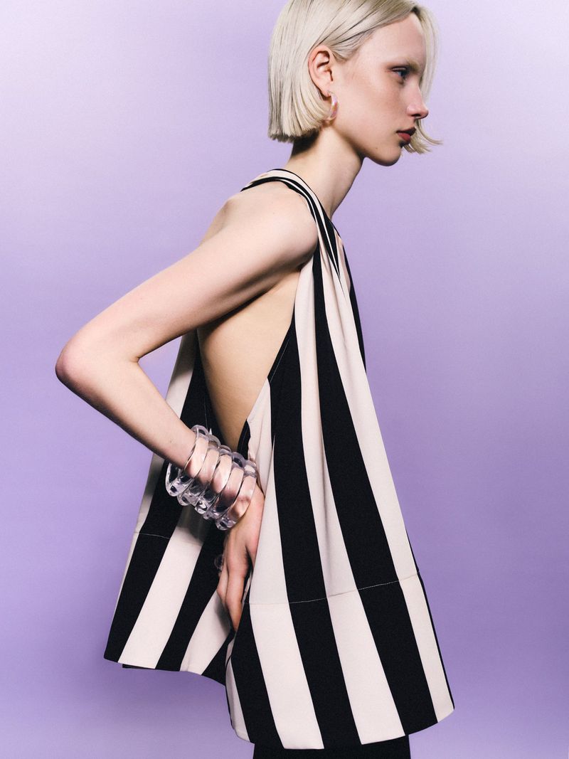 Fashion photo of a fair-skinned adult female model with platinum blonde bob haircut wearing a striped black and white sleeveless top.