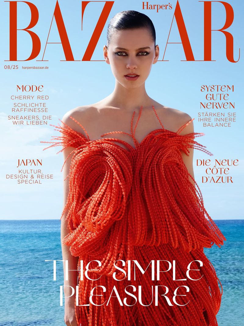 Harper's Bazaar cover featuring a woman in a red, feathered dress, shot in natural light with ocean in the background. Fashion and lifestyle theme.
