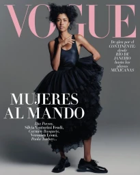 Model wearing a black dress and dark shoes standing against a grey studio backdrop for Vogue Latin America cover.