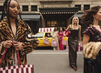 Group of diverse fashion models carrying shopping bags outside Saks Fifth Avenue in New York City.