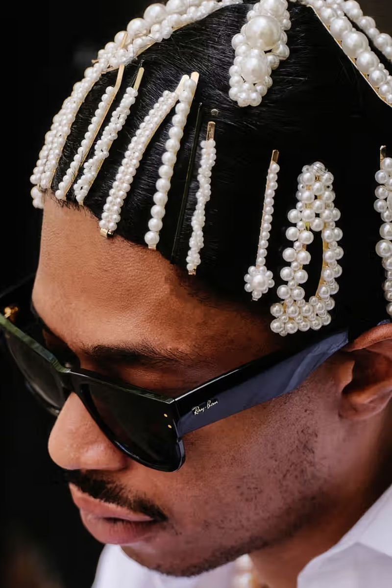 Stylish man with pearl hair accessories and sunglasses, wearing white shirt, close-up shot, fashion-forward, trendy, and sophisticated.