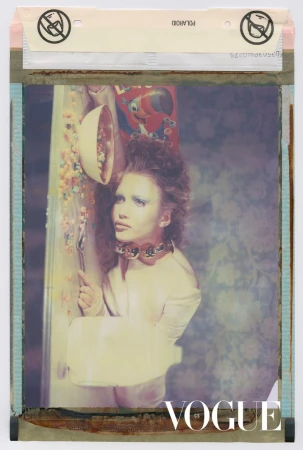 Editorial fashion shot of a young adult female model wearing a white jacket and statement necklace, posing with cereal and 'Vogue' logo.