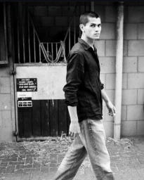 Black and white portrait of a model walking past a stable door for Numero Netherlands Serenity project
