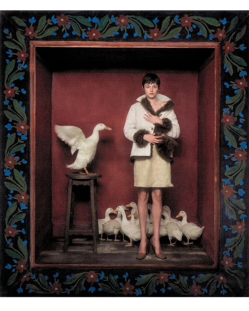 Actor Emma Corrin standing inside a dark red box surrounded by white ducks for Harper's Bazaar UK photographed by Szilveszter Mako