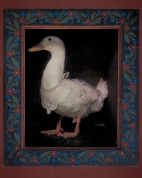 White duck wearing a small lace collar inside a dark wooden frame decorated with painted red and blue flowers