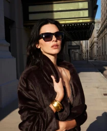 Kendall Jenner wearing dark sunglasses and a dark coat on a city street for Donna Karan New York