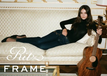 Charlotte Lawrence reclining on a cream sofa holding an acoustic guitar for FRAME 24 Hours in Paris campaign