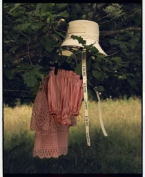 Cream bucket hat and pink satin shorts with ribbon hanging from tree branches above a green meadow