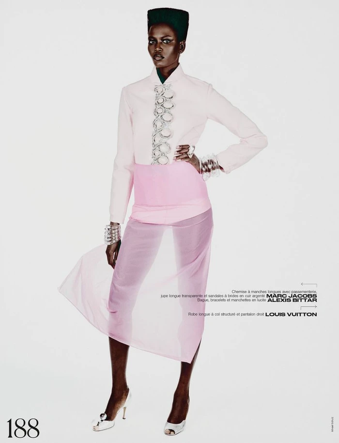 Model wearing pale pink jacket and sheer pink skirt against a plain white studio background.