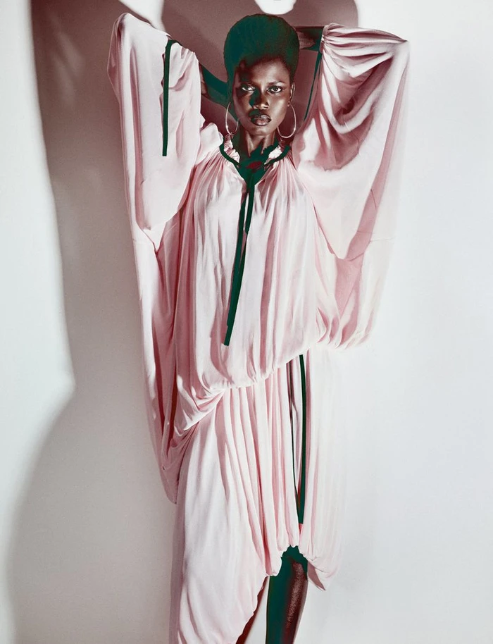 Model Ajah Angau Jok in a voluminous pink dress with dark ribbons against a white backdrop for French Magazine