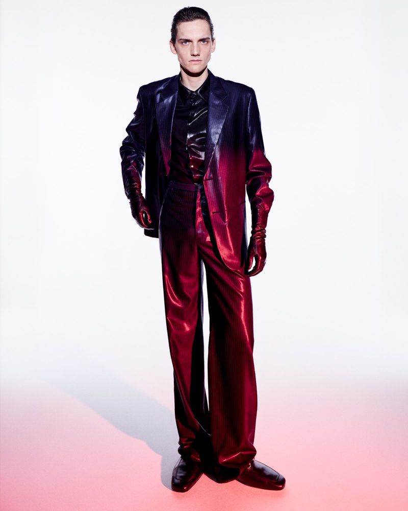 Model wearing a gradient red and black suit standing against a white backdrop