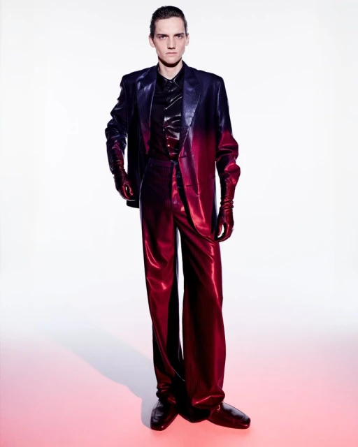 Model wearing a gradient red and black suit standing against a white backdrop