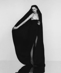 Alex Consani in a dramatic black gown with hooded cape against a seamless studio background for WSJ The New Sexy project