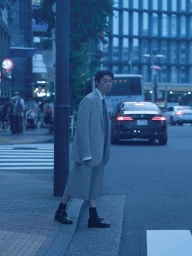 Man wearing a grey suit and shorts standing on a city street at twilight for a WSJ editorial photographed by Takashi Homma.