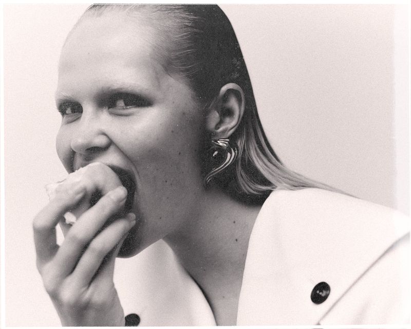Model Roos Schreiner biting an apple in a black and white editorial portrait for WRPD Magazine project La signora.