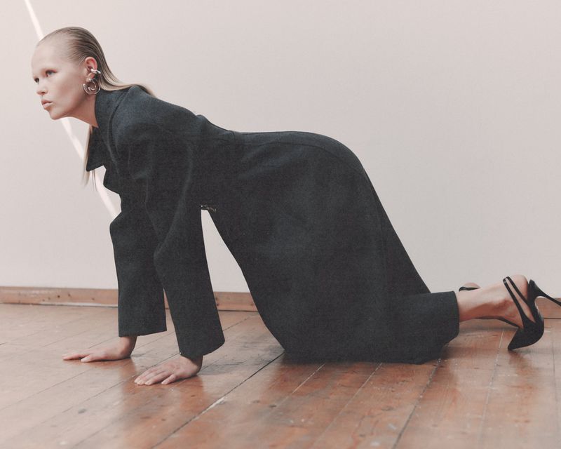 Model Roos Schreiner on all fours wearing a dark coat and high heels for WRPD Magazine