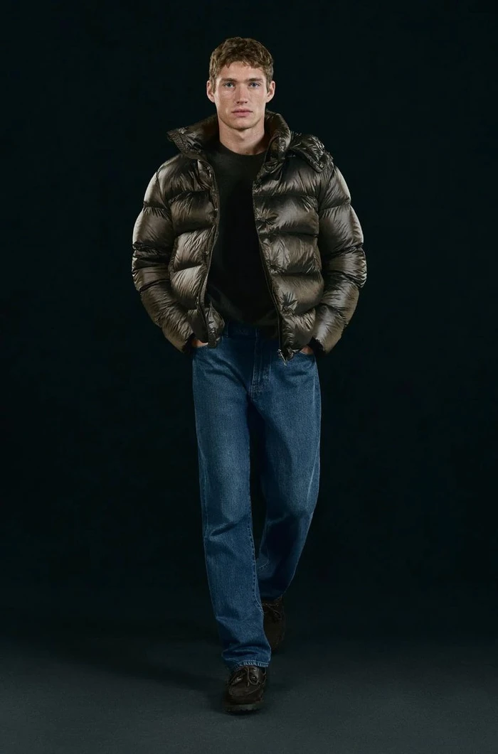 Model Valentin Humbroich in a dark puffer jacket and blue jeans against a dark background for Massimo Dutti.