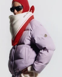 Model wearing a lavender puffer jacket, red balaclava, scarf, and dark sunglasses against a seamless white background.