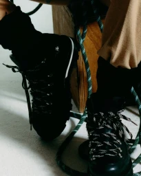 Close-up of black hiking boots with patterned laces and tan trousers for Moncler Spring 2027 by photographers Ilyes Griyeb and Mattia Parodi.