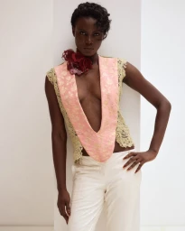Model Janet Jumbo wearing a patterned top and white trousers in EWUSIE S/S 27 lookbook.