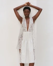 Model Janet Jumbo posing in a white lace dress with arms raised against a seamless background for EWUSIE S/S 27