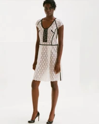 Janet Jumbo in a white lace dress with black trim standing against a white seamless background for EWUSIE lookbook