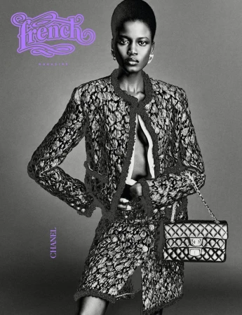 Black and white portrait of Ajah Angau Jok wearing a patterned tweed jacket and skirt set while holding a quilted chain-strap handbag.