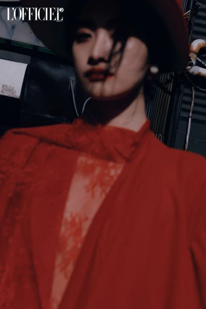 Fashion editorial image features a model in a red outfit and hat against an urban backdrop. The L'Officiel magazine logo is visible.