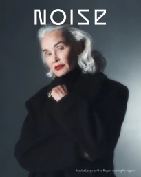 Portrait of Jessica Lange with white hair wearing a black coat against a grey gradient background for Beyond Noise Issue 6.