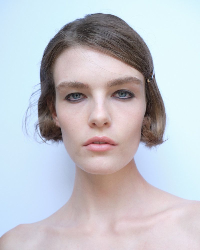 Close-up portrait of a woman with short brown hair and dark eyeliner against a plain light background for Paloma Wool S/S 27