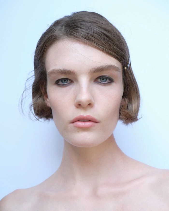 Close-up portrait of a woman with short brown hair and dark eyeliner against a plain light background for Paloma Wool S/S 27