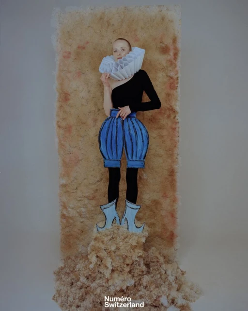 Surreal fashion portrait of a fair-skinned adult woman in a black top and cartoonish blue pants and shoes, in a studio setting.