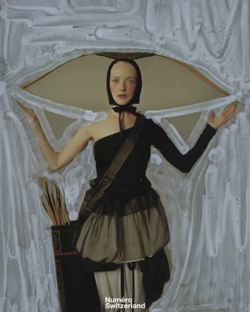 Artistic portrait of a fair-skinned woman in a black dress and head covering, posing in front of a textured abstract background.