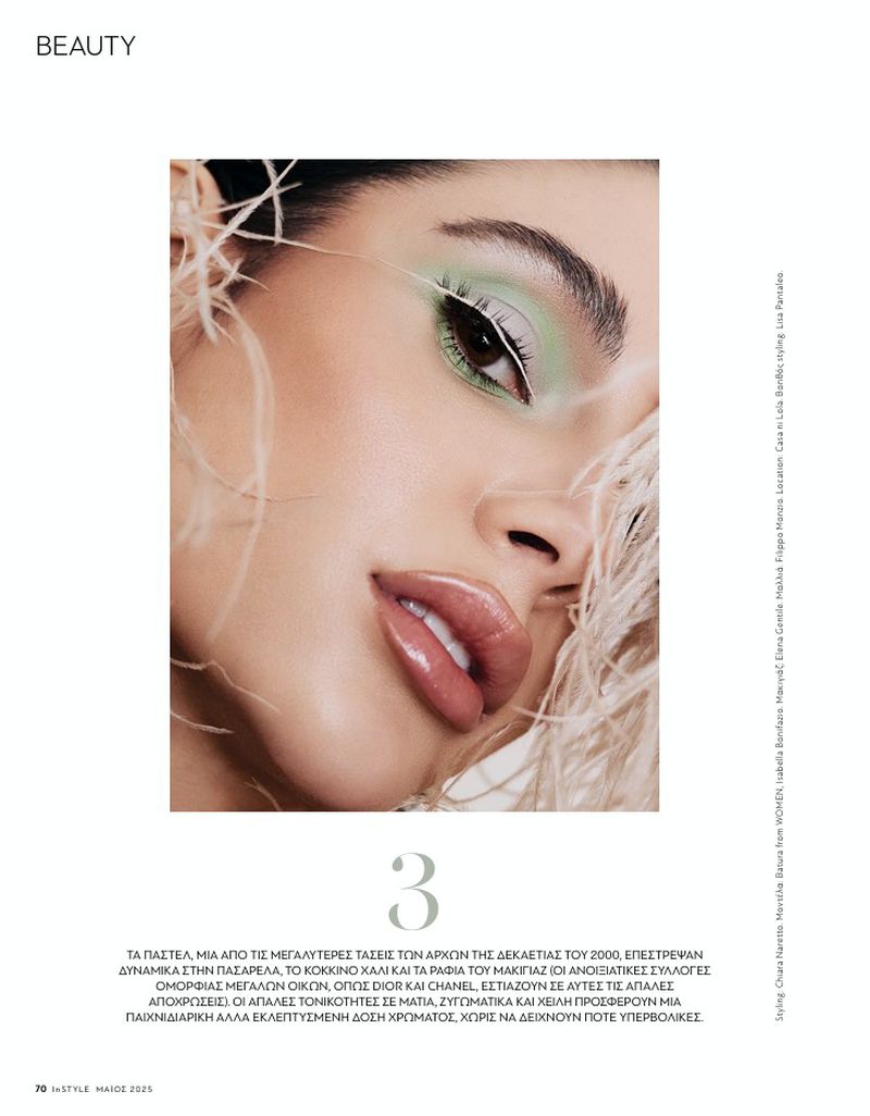 Beauty editorial shot: a woman with light green eyeshadow, glossy lips, and feathered accents poses in a close-up beauty photograph.