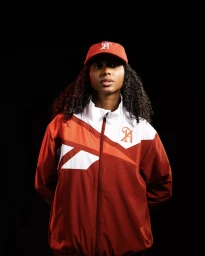 Woman wearing a red and white jacket and matching cap against a solid black background for Ultimate Sevens brand identity