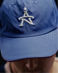 Close up of a blue baseball cap with white embroidered logo for Ultimate Sevens brand identity