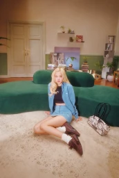 ROS seated on a rug wearing a blue denim jacket and skirt in a living room for Puma Speedcat Croc.
