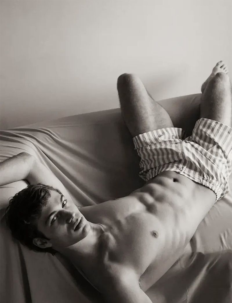 Athletic man lying on a bed in boxer shorts in a black and white portrait, creating a relaxed and intimate atmosphere in a bedroom.