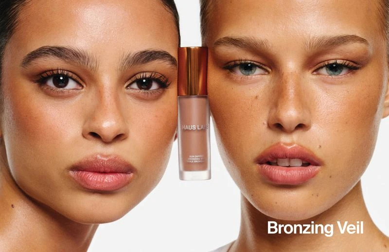 Two models showcasing a bronzing product bottle held between their faces against a white background for Haus Labs