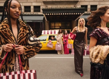 Group of models in luxury eveningwear and coats holding shopping bags on a city street outside Saks Fifth Avenue